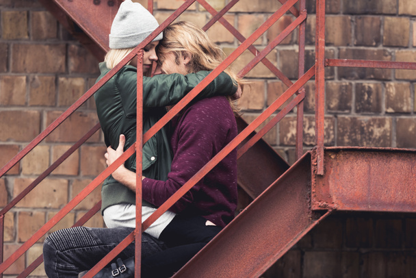 pareja sentada en escaleras y abrazando
 - Foto, imagen