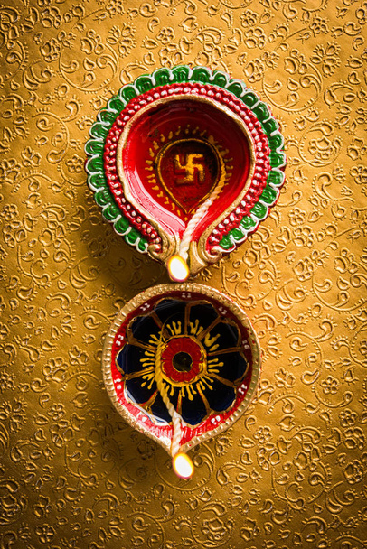 Склад фото красивой diwali diya с подарками и цветами, на декоративном фоне, угрюмое освещение и избирательный фокус
 - Фото, изображение