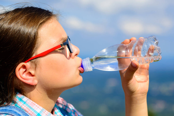 Молодая девушка пьет воду на открытом воздухе
 - Фото, изображение