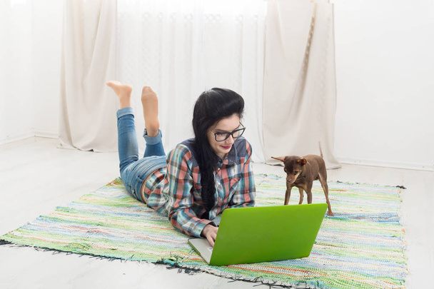 Jong meisje op vloer met laptop en hond - Foto, afbeelding