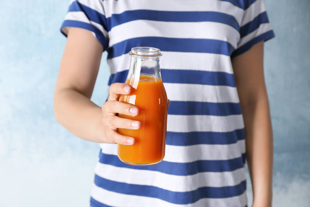 Woman holding bottle of fresh carrot juice - 写真・画像