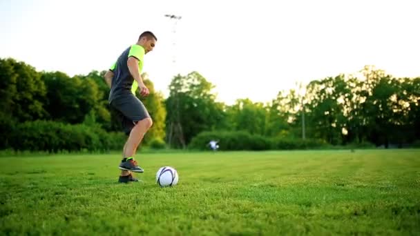 Close-up van benen en voeten van voetballer in actie voor het dragen van zwarte schoenen uitgevoerd en dribbelen met de bal spelen op gras worp geïsoleerd op zwarte achtergrond - Video