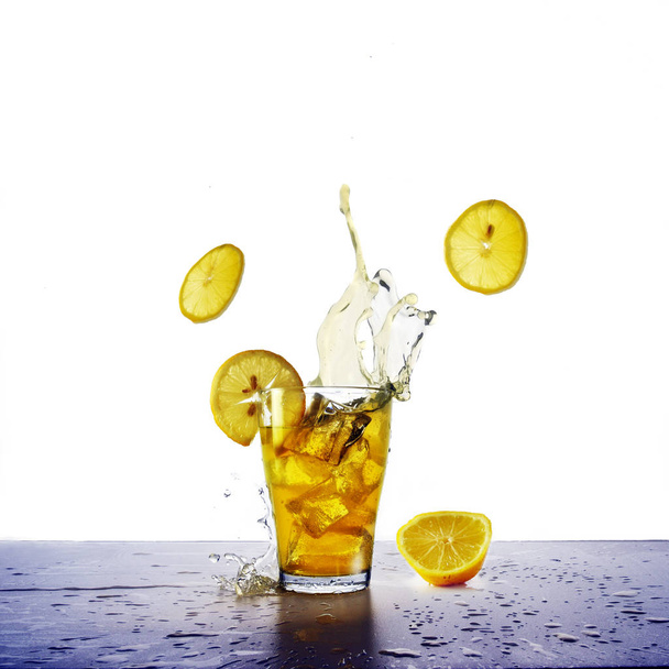 yellow drink with splash, ice cubes and flying lemons slices,  refreshing beverage from juice, soda or ice tea isolated - Valokuva, kuva
