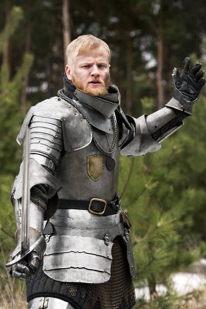 Knight in armour during battle on forest background - Foto, imagen