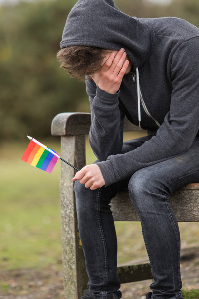 Depressed teenage boy holding a pride flag - Foto, imagen
