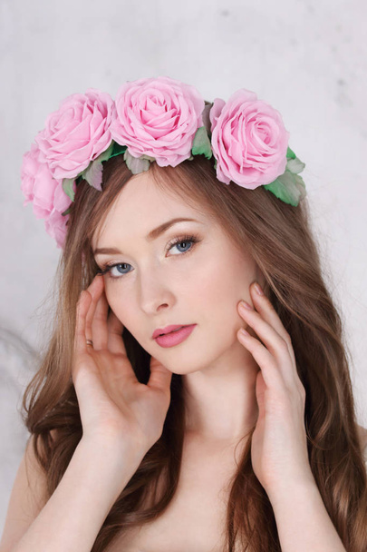 Beautiful woman in roses wreath with long hair poses in white st - Foto, afbeelding