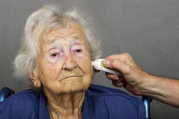 Seniorin lässt Temperatur überprüfen - Foto, Bild