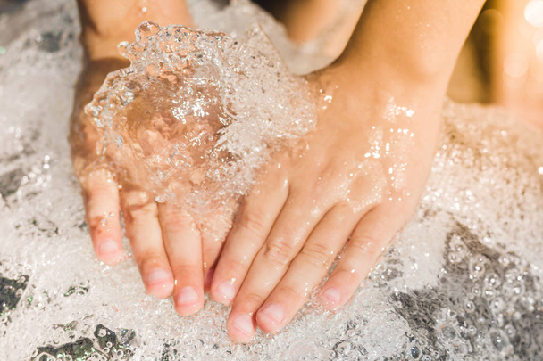 Hands of a boy with a splash of water, backlit in the evening su - Фото, зображення