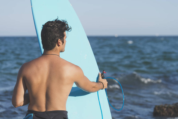 Surfista sosteniendo su tabla de surf azul
 - Foto, imagen
