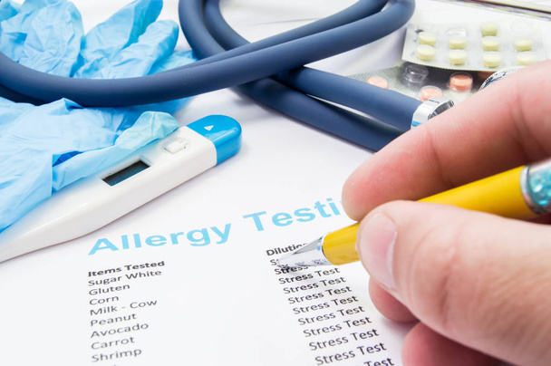 Doctor checks patient's allergy analysis near stethoscope and thermometer. Scene from work or professional activities of general practitioner, allergist, pediatrician or therapist in allergy treatment - Photo, image