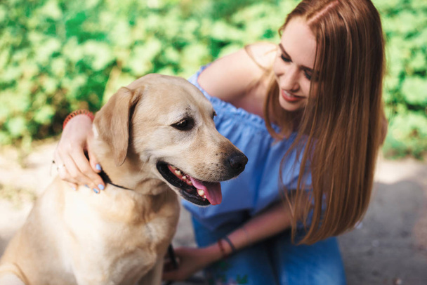 Beauty woman with her dog playing outdoors - Photo, image