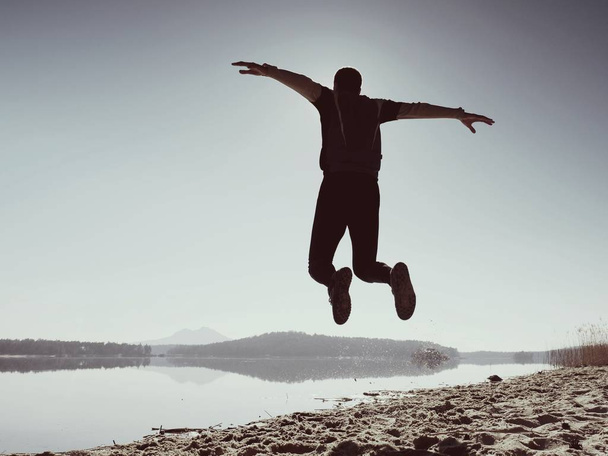 Saltando hombre. Deportista loco saltando y trotando en la playa durante el amanecer
 - Foto, imagen