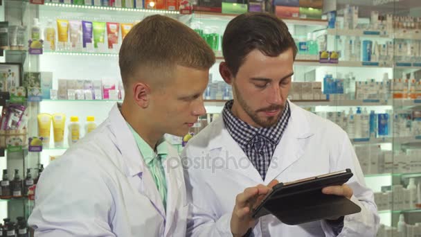Δύο φαρμακοπώλη χρησιμοποιώντας ένα tablet στο χώρο εργασίας - Πλάνα, βίντεο