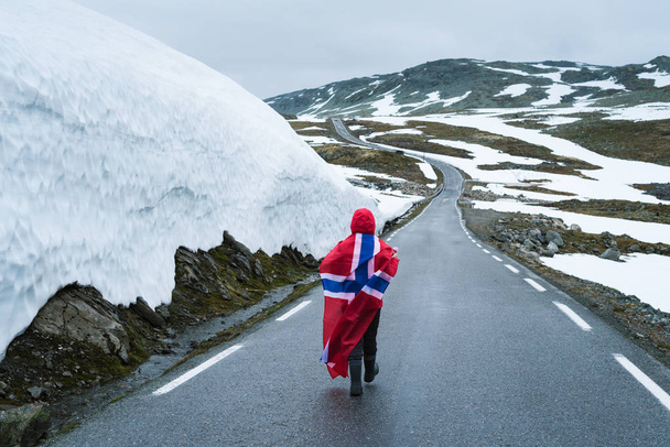 Meisje met een Noorse vlag op een besneeuwde weg in Noorwegen - Foto, afbeelding