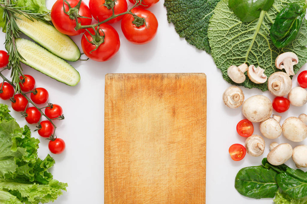 Brown wood cutting board, border of fresh vegetables on white background with copy space - Photo, Image