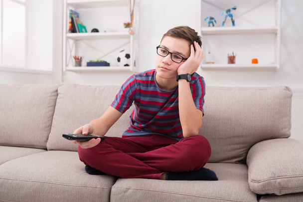 Boy watching tv and looking bored on couch at home - Photo, Image