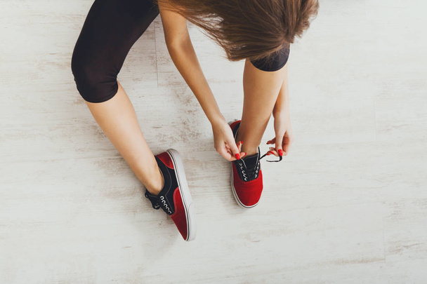 Жінка зав'язує мереживо на спортивне взуття вид зверху
 - Фото, зображення
