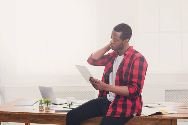 Zestresowany biznesmen czarny w nowoczesnym biurze, praca z tabletem - Zdjęcie, obraz