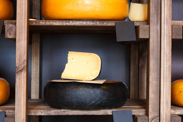 Жесткий сыр, как колесо и кусок на полке продуктового магазина
 - Фото, изображение