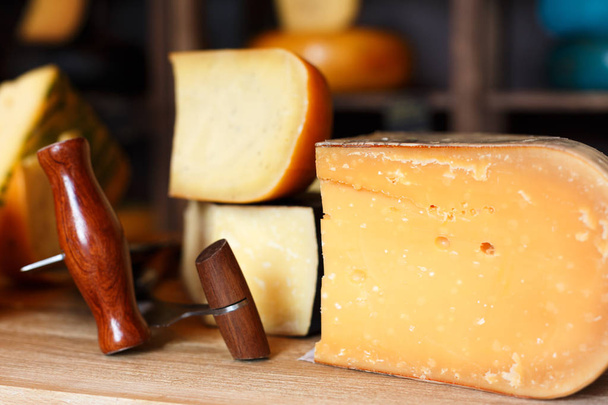 Ассортимент твердых сыров в продуктовом магазине крупным планом
 - Фото, изображение