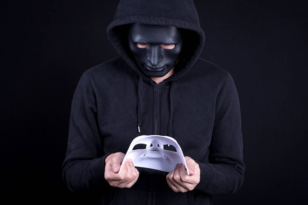 Hombre misterioso sosteniendo y mirando la máscara blanca
 - Foto, imagen