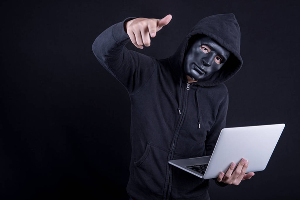 Hacker masculino com máscara preta carregando laptop
 - Foto, Imagem