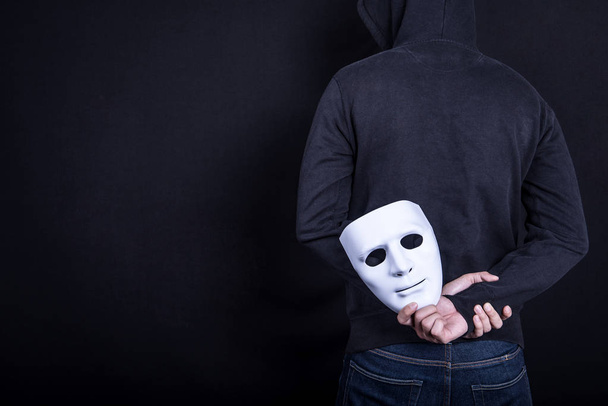 Mystery man holding white mask in the back - Foto, Bild