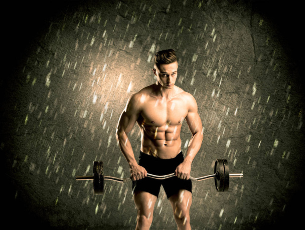 Fitness chico con peso mostrando los músculos - Foto, imagen