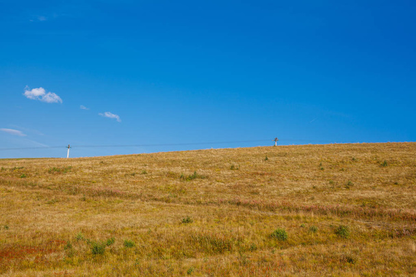 сушена осіння трава на тлі гір і блакитне небо з хмарами
 - Фото, зображення