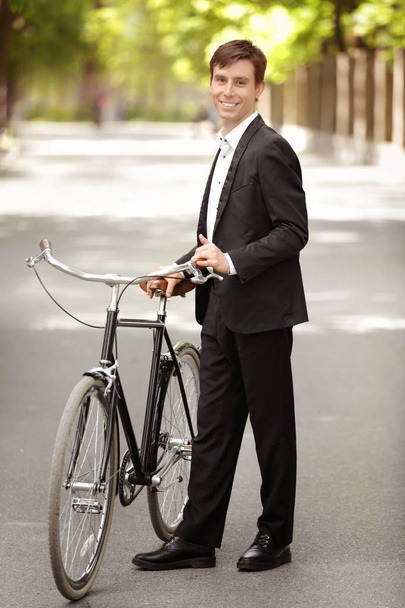 Young handsome businessman with bicycle outdoors on sunny day - Фото, зображення