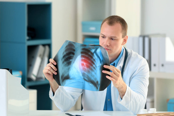 Doctor with x-ray image at table in hospital. Lung cancer concept - Foto, imagen