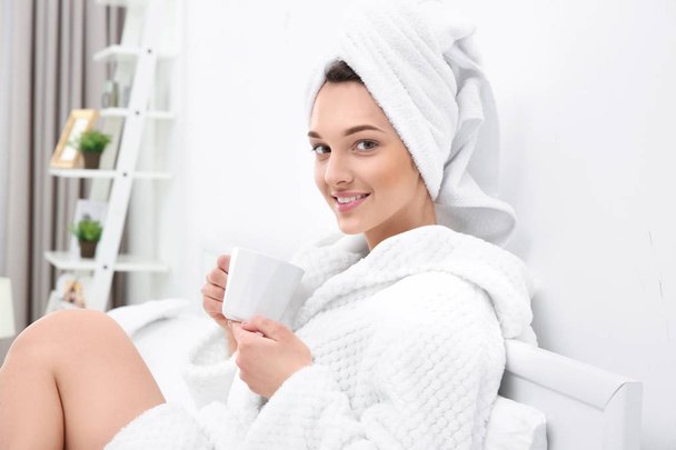 woman after shower in bathrobe with cup of coffee  - 写真・画像
