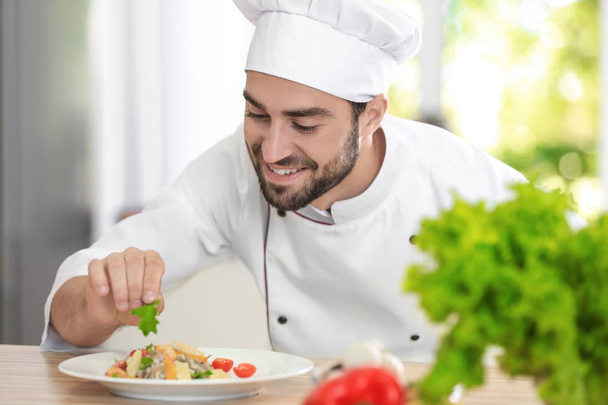 Young male chef garnishing his dish - Foto, afbeelding