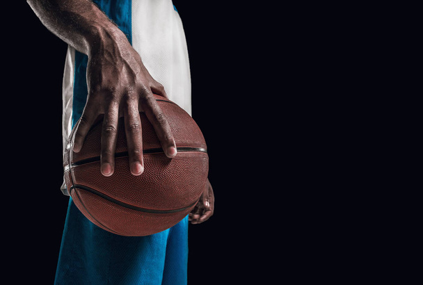 The hand of a basketball player with a ball against dark studio background. advertising concept - Fotografie, Obrázek