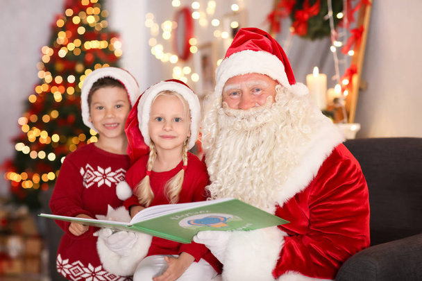Authentic Santa reading book to cute kids in room with beautiful Christmas decorations - Photo, Image