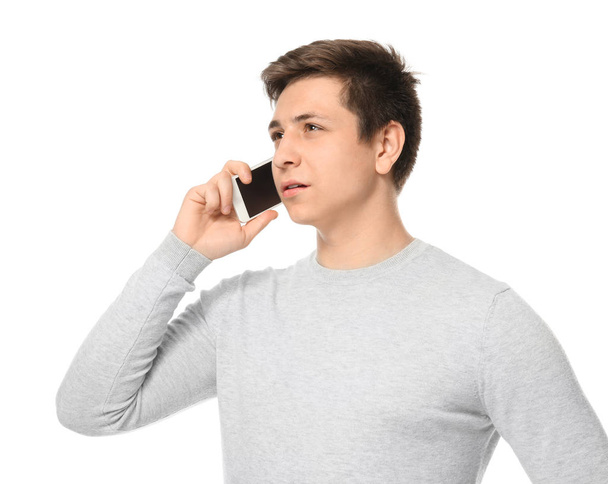 Cute teenage boy with mobile phone on white background - Foto, imagen