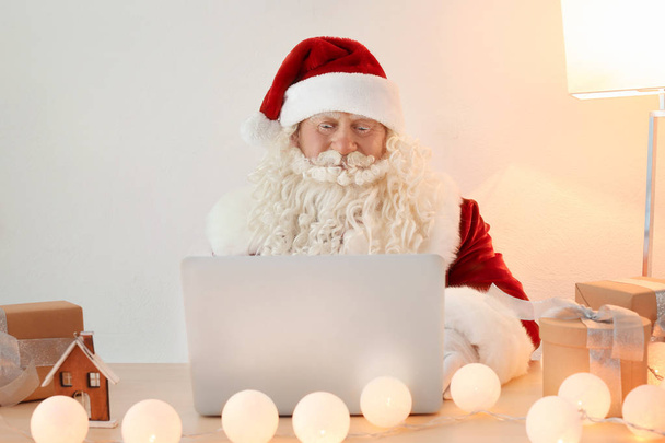 Santa Claus using laptop  - Фото, изображение