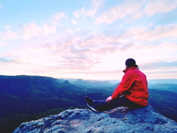 Hiker man take a rest on mountain peak. Man lay on summit, bellow autumn valley. Bright morning Sun shining in sky.  - Φωτογραφία, εικόνα