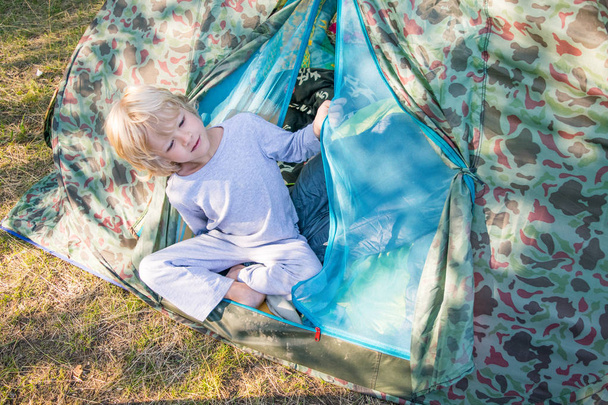 Sleepy blond boy gets out a tent in a morning - Foto, immagini