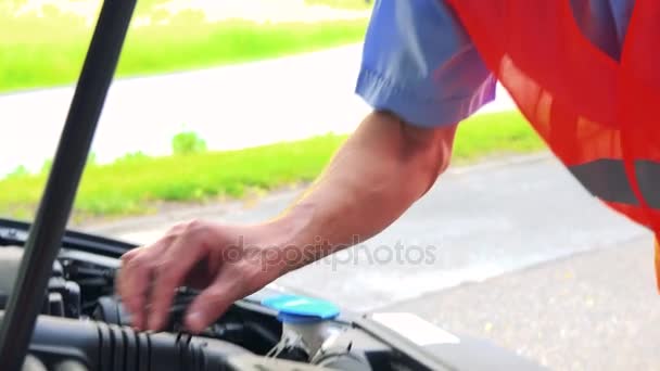 Старший чоловік носить попереджувальний жилет і керує двигуном автомобіля крупним планом двигуна і обличчя людини
 - Кадри, відео