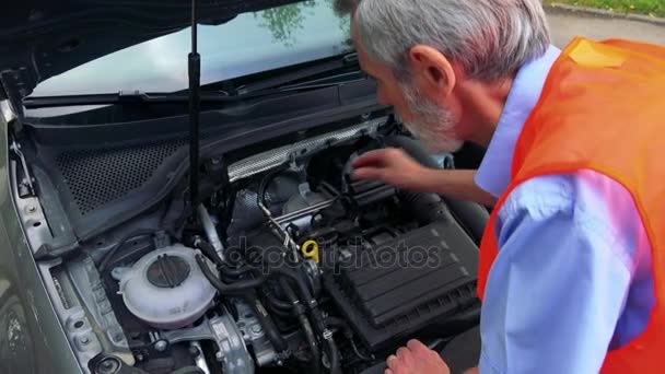 Senior man draagt veiligheidsvest en controles van de motor van de auto - closeup - Video