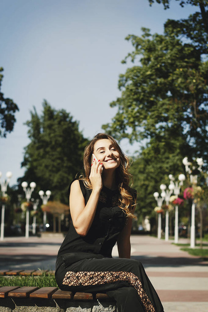 Nuori kaunis nainen puhuu puhelimessa istuu puistossa
 - Valokuva, kuva