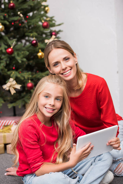 family using digital tablet at christmas tree  - Zdjęcie, obraz