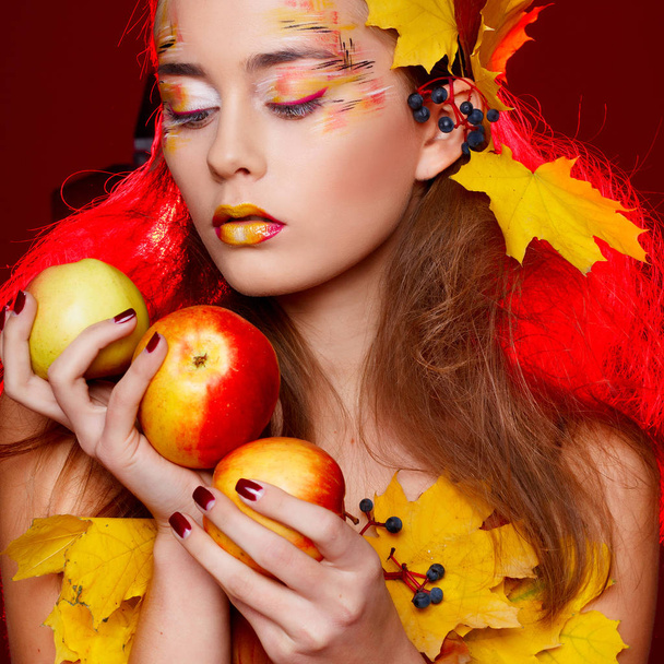 Όμορφη νεαρή γυναίκα με το φθινόπωρο συνθέτουν κρατώντας τα μήλα της  - Φωτογραφία, εικόνα