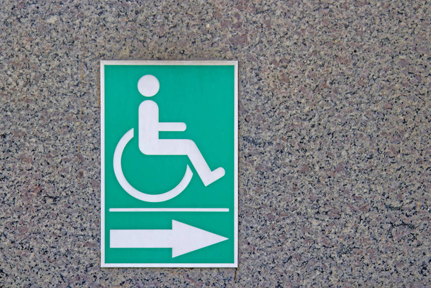 Symbol für Behinderte auf dem grünen Stock an den Marmorwänden. - Foto, Bild
