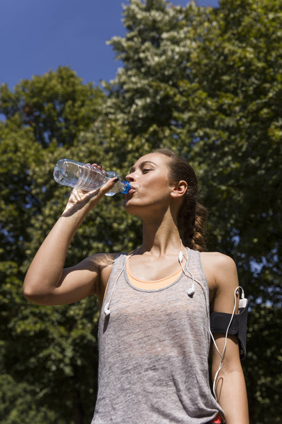 hübsche junge Frau trinkt Wasser während des Trainings - Foto, Bild