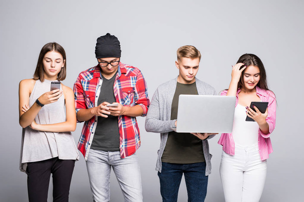 Groep van gelukkige jonge mensen zittend op de Bank en het gebruik van digitale tablet en laptop, geïsoleerd op witte achtergrond. - Foto, afbeelding
