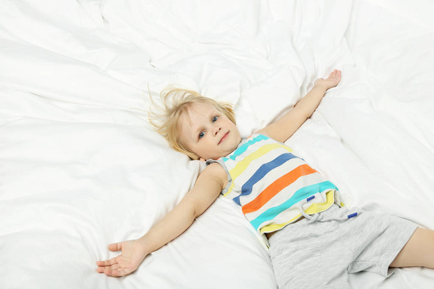 Little boy lying in white bed - Zdjęcie, obraz