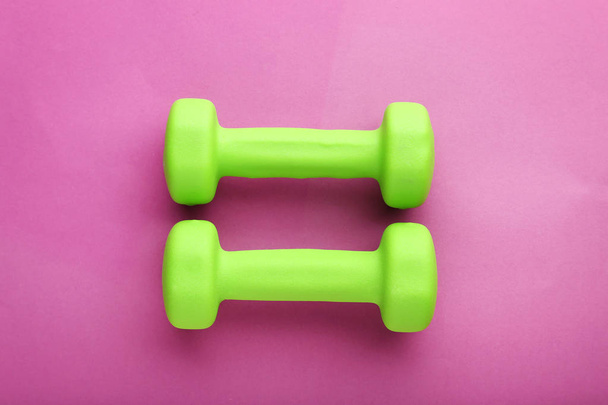 Green dumbbells on pink background - Foto, immagini
