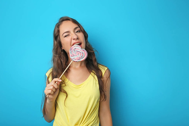 Portrait of young woman with lollipop on blue background - Foto, Imagen
